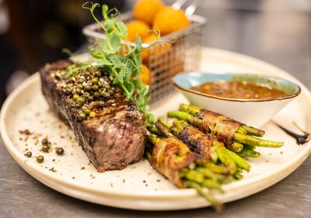 Plate with meat, beans in bacon, sauce and side dish