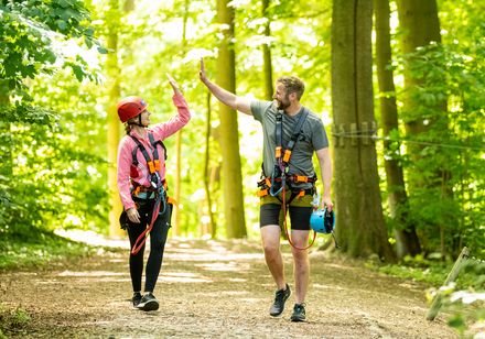 Two people in a climbing park giving each other a high five