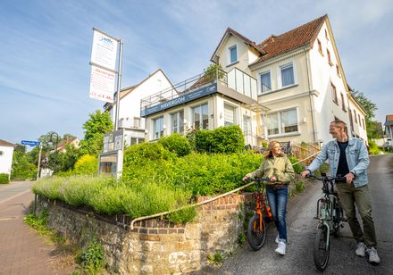 Two cyclists push their bikes along the wall of the Havergoh hiking and cycling hotel.