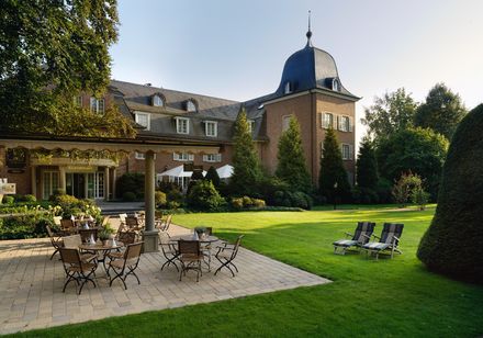 Historic monastery building surrounded by greenery with terrace