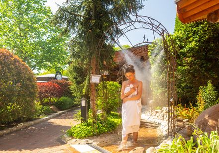 Woman walking through mist in the sauna garden with a towel
